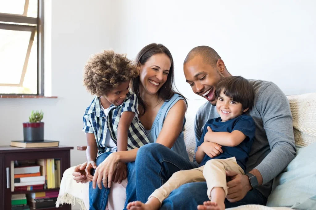 Family of four on a couch smiling - Keep pests away from your home with Active Pest Control in NY